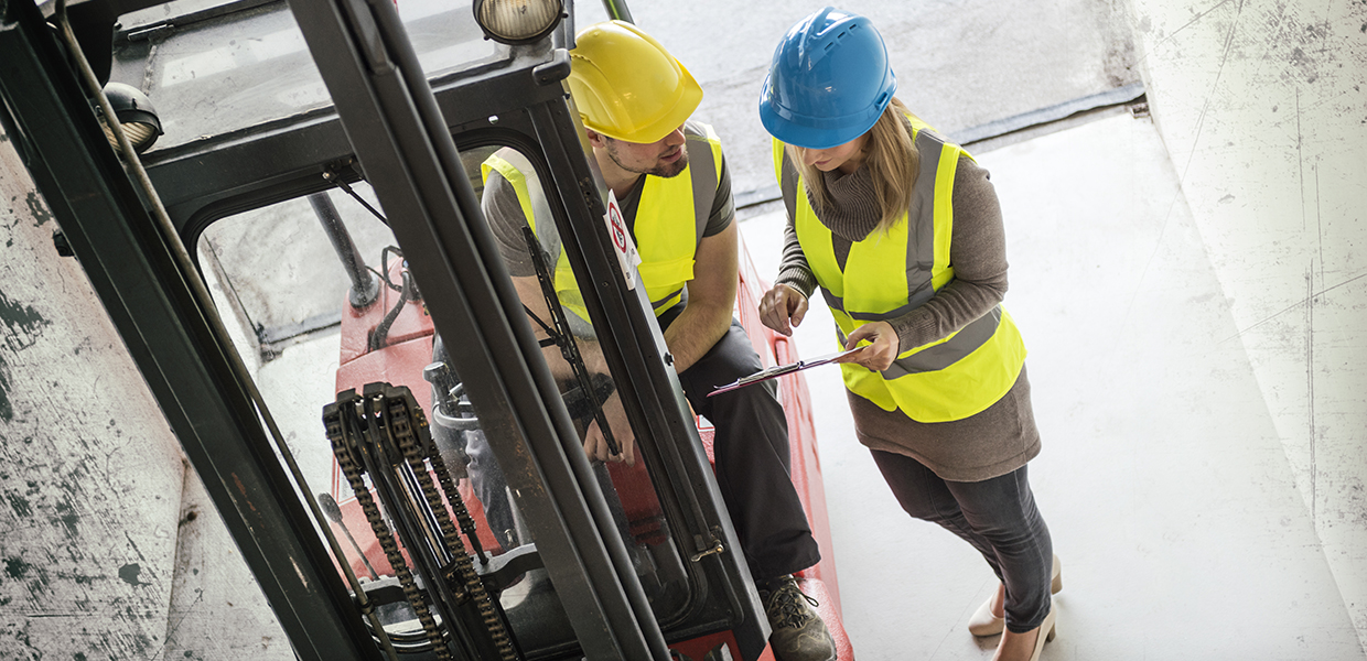 Driver of forklift and business woman checking a list.