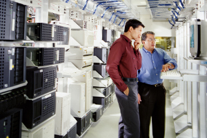 Two businessmen using computer in server room