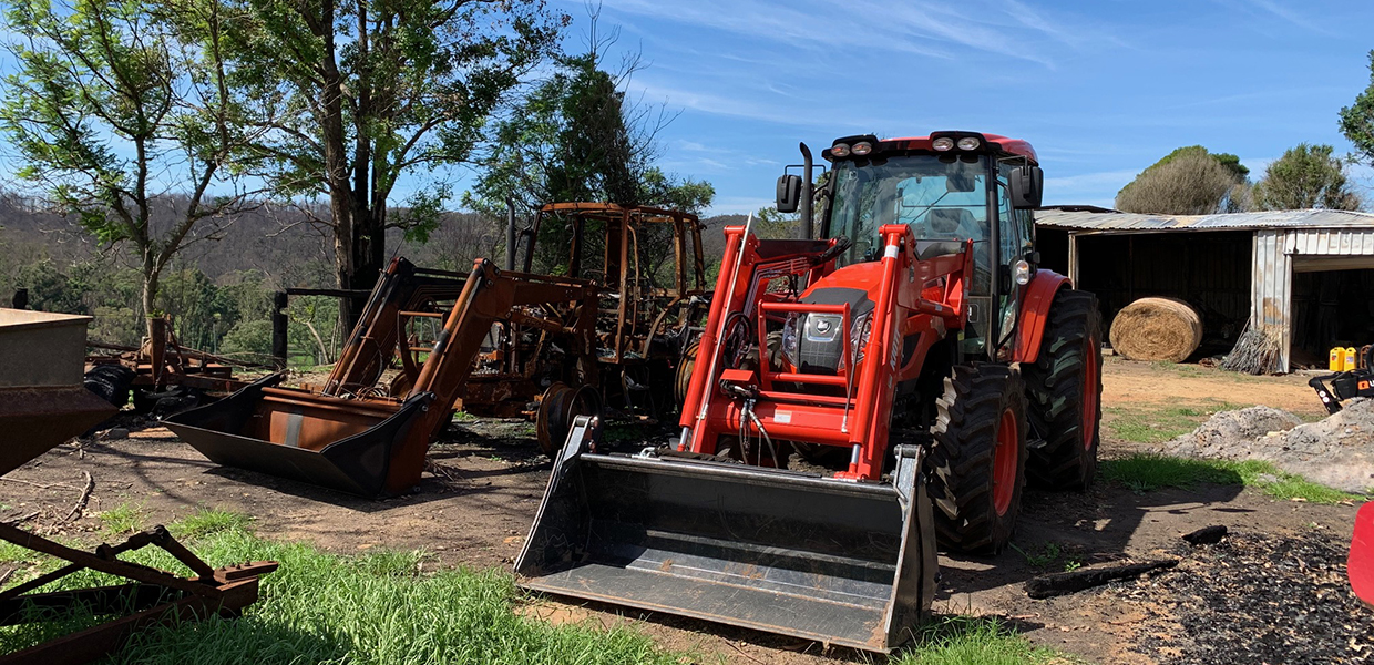 A burned tractor next to a new tractor