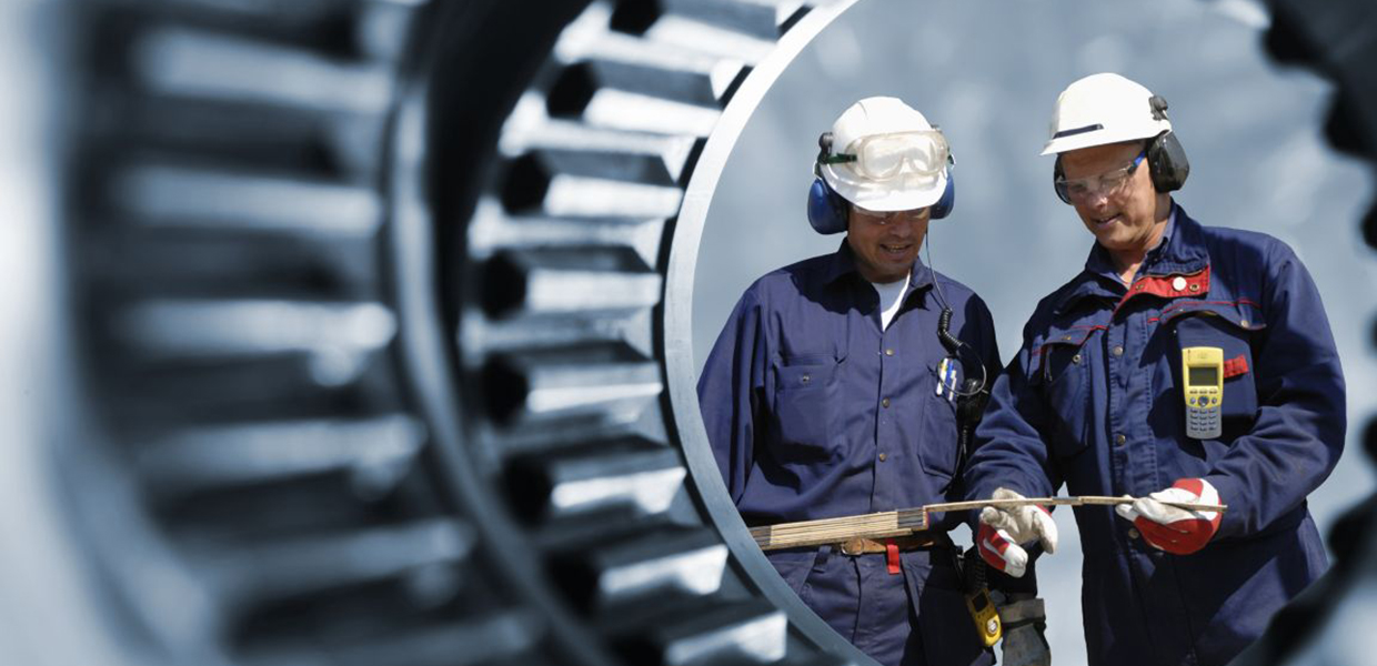 Two workmen shown through some big gears