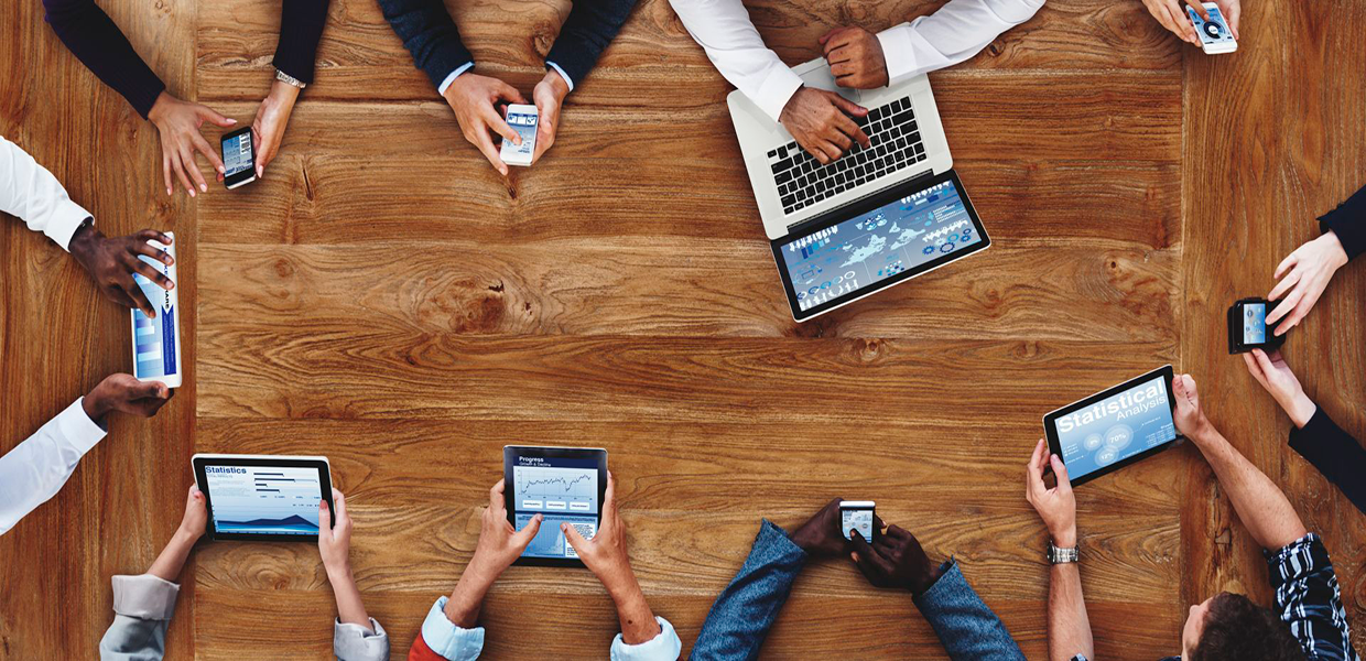 People around a table with different devices