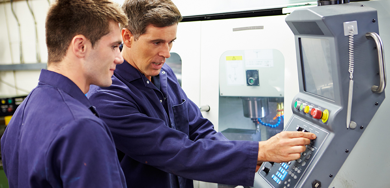 Two workmen in front of CNC machine