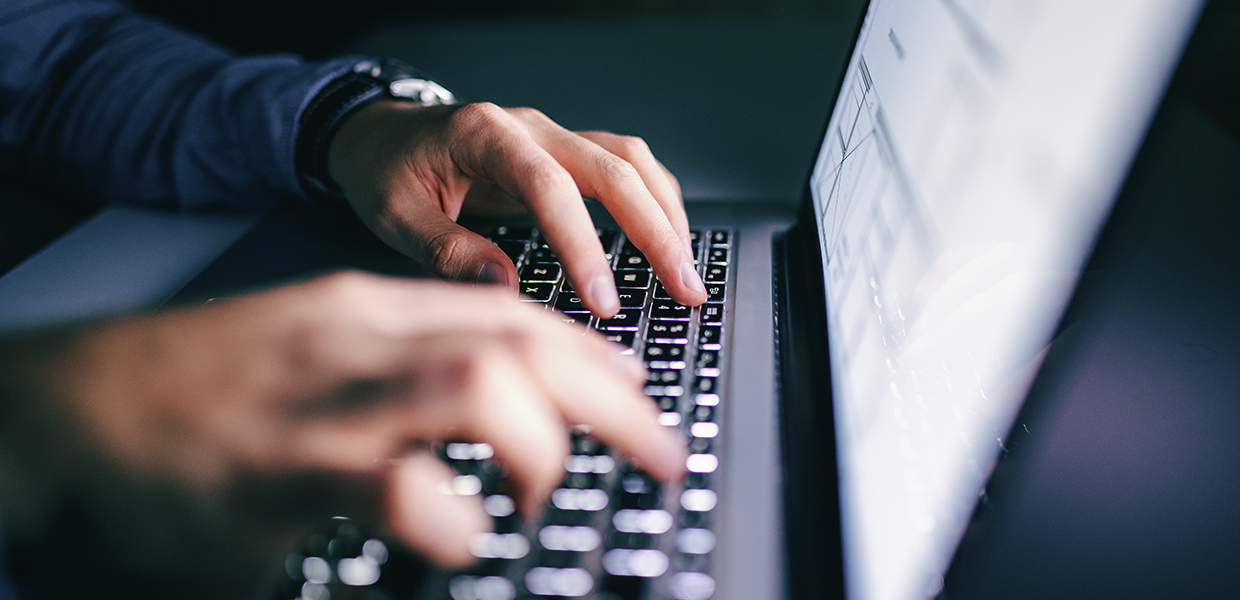 Hands typing on a laptop