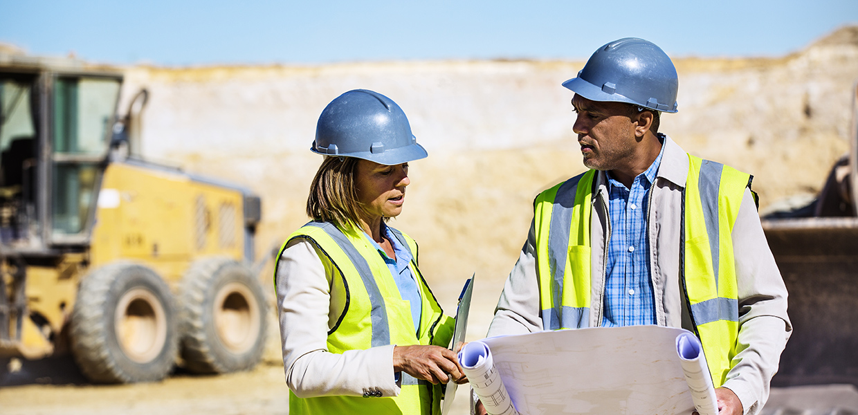 Construction workers in hard hats looking over blueprint